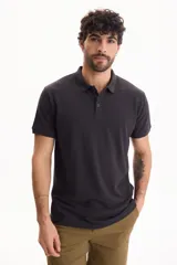 Remera polo de piqué color negro, con mangas cortas y cierre frontal de tres botones.