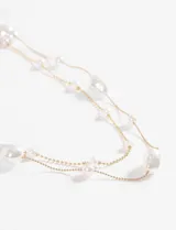 Collar de doble cadena fina dorada decorado con perlas blancas de diversos tamaños y formas irregulares.