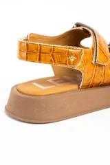 Sandalias de cuero color caramelo con textura efecto cocodrilo, suela chunky marrón y tiras ajustables con velcro.