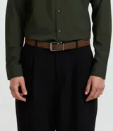 Cinturon reversible negro para hombre, de cuero sintetico con textura y hebilla metalica cuadrada de color plateado oscuro.