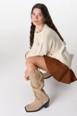 Bota de caña alta color beige, de cuero gamuzado, con taco cuadrado y punta cuadrada.