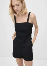 Mono corto de diseño recto y escote cuadrado, con tirantes anchos y cinturón decorativo a tono. Cuenta con bolsillos laterales y cierre de cremallera invisible en la parte posterior.