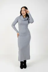 Vestido largo de punto color gris, con cuello tipo polera holgado y mangas largas. Presenta un corte ajustado al cuerpo y diseño minimalista.