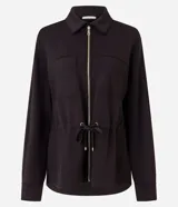 Campera tipo parka color verde oscuro, confeccionada en modal con cierre frontal metálico, cuello camisero, bolsillos frontales y cordón ajustable en la cintura.
