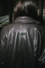 Campera tipo bomber de cuero sintético color marrón, con cuello clásico, cierre frontal completo y puños y ruedo elásticos.
