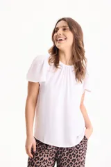 Blusa blanca de manga corta, con pliegues en el escote redondo y confeccionada en tela crepé.