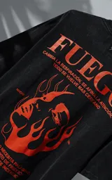 Remera de manga corta con cuello redondo y calce oversize, color negro con efecto nevado. Presenta una estampa frontal en color naranja con diseño gráfico de un rostro rodeado de llamas y texto tipográfico.