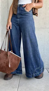 Jean de corte ancho y tiro medio, confeccionado en denim azul oscuro sin lycra. Presenta un diseño de pierna recta y holgada con costuras reforzadas.