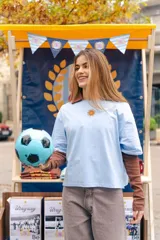 Remera de algodón color celeste, con cuello polo en color marrón y bordado de un sol en el centro del pecho.
