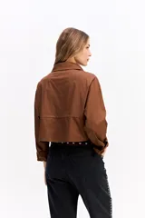 Camisa crop de corte relajado, con cuello clásico, cierre frontal de botones y mangas largas con puños. Confeccionada en algodón, presenta un diseño versátil y moderno.