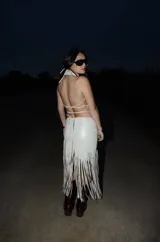 Pollera midi de cuero color hielo, de silueta al cuerpo y con detalle de flecos largos en la parte inferior.