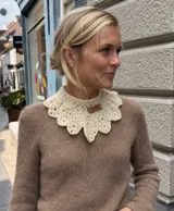 Cuello tejido a mano en lana merino, con diseño de encaje festoneado y etiqueta de cuero con marca grabada.