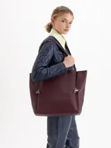 Cartera tipo shopper de cuero vacuno flor graneado, con formato amplio y estructura flexible. Presenta dos cierres verticales decorativos en el frente con tiracierres personalizados y doble manija de hombro.