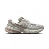 Championes Nike V2K Run de estilo retro-futurista, con diseño en capas de malla y materiales sintéticos en tonos beige y gris. Presentan una entresuela robusta con tecnología Cushlon y el icónico logo Swoosh en los laterales.