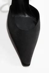 Zapatos de taco alto confeccionados en satén negro, con diseño de punta fina y taco de carrete revestido. Cuenta con tiras cruzadas y pulsera ajustable con hebilla metálica en el tobillo.