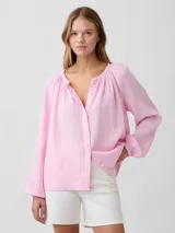 Camisa de muselina color rosado, de corte holgado, con mangas largas abullonadas y cierre frontal con botones.