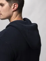 Campera tejida con capucha, confeccionada en poliéster, con cierre frontal completo y diseño de punto acanalado.