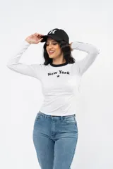 Remera de manga larga ajustada al cuerpo, color negro con cuello redondo blanco y franjas blancas laterales en las mangas. Presenta un estampado frontal con la inscripción 'Los Angeles' y una estrella pequeña.