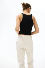 Pantalón tobillero cigarette de color beige en tejido elástico, con cintura estándar, bolsillos al bies y piernas ajustadas con raya marcada.