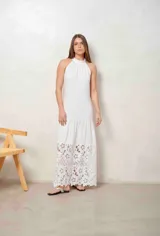 Vestido largo beige con cuello halter y detalle de broderie calado en el dobladillo inferior.