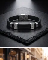 Pulsera de goma negra con detalles en acero inoxidable plateado que incluyen apliques con diseño de guarda griega y cierre de seguridad.