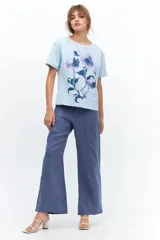 Remera lila de algodón con estampado de flores en tonos naranja y rosa.