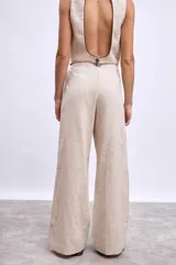 Pantalon de vestir de corte recto y tiro alto, confeccionado en tela de lino en color beige. Presenta pinzas frontales, cierre con botón y detalle de vivos en contraste en la cintura.