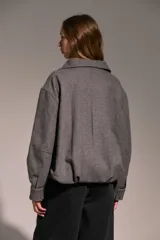 Campera bomber de paño gris con cuello alto, cierre frontal con botones a presión y cinturón integrado en el ruedo.