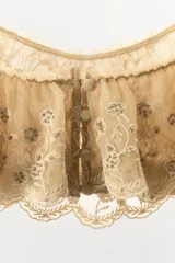 Top corto de escote recto con tirantes finos ajustables mediante lazadas. Presenta un diseño de tejido superpuesto tipo volante con bordados florales y detalles de abalorios a contraste. Cuenta con cierre posterior mediante botones forrados.