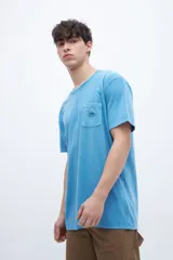 Remera celeste de algodón con bolsillo en el pecho, teñida en prenda. Tiene una etiqueta en el bolsillo y un estampado en la espalda.
