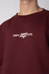 Buzo de cuello redondo confeccionado en tejido rústico, con diseño boxy, costuras a la vista y bordes al corte. Presenta estampas en el frente, la espalda y el interior, permitiendo un uso reversible.
