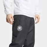 Pantalón deportivo Adidas de la selección alemana, color negro, con ajuste holgado y puños elásticos en los tobillos. Presenta el escudo de la DFB en la pierna derecha y el logo de Adidas en la izquierda, con bolsillos laterales con cierre.