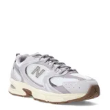Championes New Balance modelo 530, con diseño retro-deportivo. Presentan una capellada de malla blanca transpirable con refuerzos sintéticos en tonos gris claro y lila. Incorporan entresuela con tecnología ABZORB para amortiguación y suela de goma en color marrón.