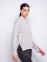 Suéter gris de punto con cuello alto, mangas largas y anchas, detalle de línea vertical rosa contrastante en las mangas y aberturas laterales.