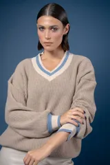 Buzo de punto en color azul marino con escote en V, puños y cuello con detalles en franjas de color turquesa y rojo. Presenta un diseño holgado de manga larga.
