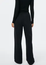 Pantalón de corte recto y holgado, color blanco, con cintura elástica y cordón ajustable. Presenta costuras verticales frontales que estilizan la silueta.