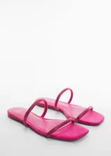 Sandalia plana de diseño minimalista en color fucsia, con dos tiras finas decoradas con strass y punta cuadrada.