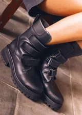 Botas altas de cuero marrón con suela track y tres tiras con hebillas metálicas en la caña.