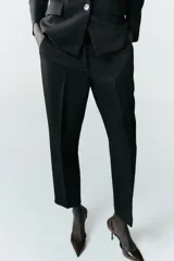 Pantalón de corte recto y largo tobillero, con tiro medio. Presenta bolsillos frontales, falsos bolsillos traseros de vivo y cierre frontal con cremallera, botón interior y ganchos.