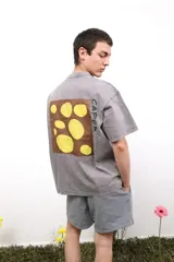 Remera de algodón con cuello redondo, manga corta y calce holgado. Presenta un diseño minimalista con un pequeño logo estampado en el pecho y una estampa de mayor tamaño en la espalda.