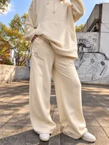 Pantalón jogger ancho color beige, con bolsillos laterales y pequeño bordado de un arco y flecha en la parte superior.