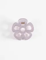 Broche para el pelo con forma de flor calada, fabricado en material translúcido con mecanismo de pinza metálica.