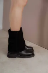 Bota de caña media combinada en cuero vacuno y gamuza, con diseño de solapa superior y punta cuadrada. Cuenta con suela de goma plana y tacón bajo.