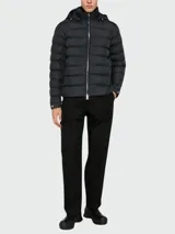 Campera puffer negra con capucha, cierre frontal con cremallera plateada y bolsillos laterales con cierre. Es reversible y está rellena de plumas.