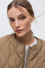 Campera acolchada marrón tipo puffer de nylon guateado, con diseño matelasseado de rombos, cuello redondo y cierre frontal. Cuenta con hombros caídos, mangas largas, bolsillos laterales discretos y cordón de ajuste en la cintura con tiras colgantes.