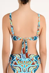 Top de bikini con escote en V profundo y detalle de herraje metálico en forma de U en el centro. Presenta un estampado geométrico multicolor en tonos terracota, azul y blanco.