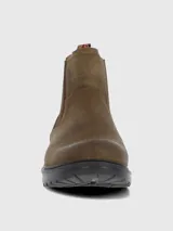 Bota estilo Chelsea color marrón, confeccionada en cuero con paneles elásticos laterales en tono marrón oscuro. Presenta una suela de goma robusta y flexible con tecnología de absorción de impactos y una tira decorativa en la parte trasera con diseño de bandera.