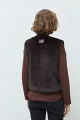 Chaleco reversible de corte recto, con un lado de cuero sintético color chocolate y el otro lado de piel sintética al tono. Presenta cuello redondo y diseño sin mangas.