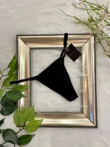 Pack de tres tangas de algodón con tiras laterales regulables. El conjunto incluye una prenda negra, una blanca y una color champagne.
