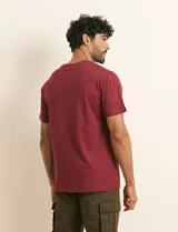 Remera básica de algodón color beige, de manga corta, con cuello redondo y un pequeño detalle bordado en el pecho.